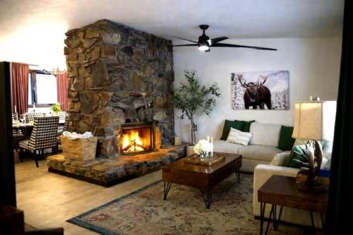 a living room with a couch and a stone fireplace at Whole House Aurora View with Hot tub, Sauna and AC in Fairbanks