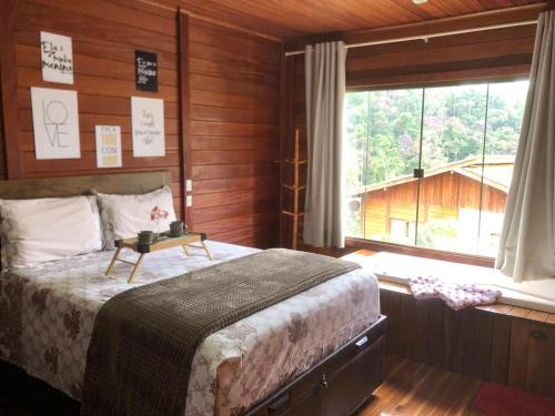 a bedroom with a bed and a large window at Chalé Beijinho in Venda Nova do Imigrante