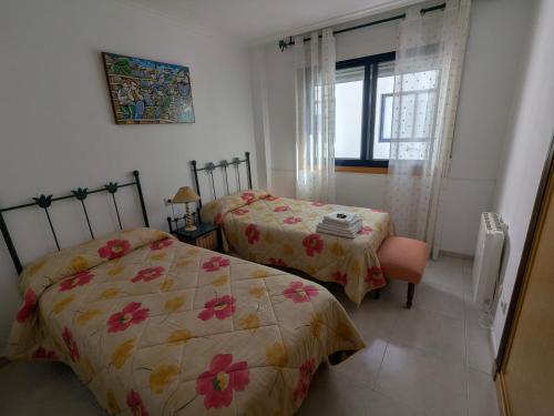 a bedroom with two beds and a window at L&C Codesal in Sanxenxo