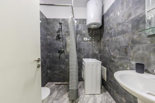 a bathroom with a shower and a toilet and a sink at Beachfront Apartment with Pool Access by PikHost in Lezhë