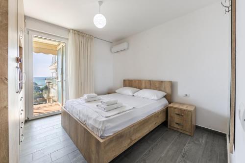 a bedroom with a large bed and a balcony at Beachfront Apartment with Pool Access by PikHost in Lezhë