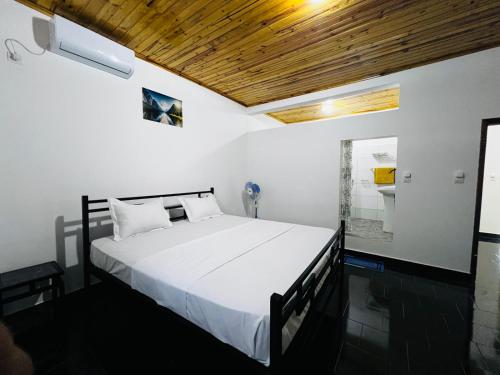 a bedroom with a white bed with a wooden ceiling at L'Appart des Amis in Antsiranana