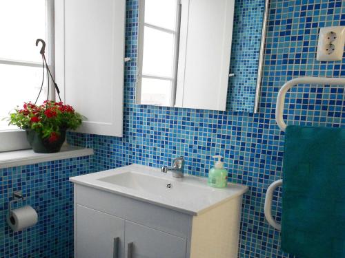 La salle de bains est pourvue de carrelage bleu, d'un lavabo et d'un miroir. dans l'établissement Apartamento Alfama 28, à Lisbonne