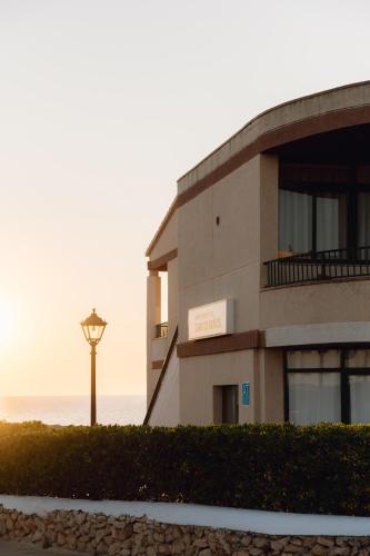 a building with a street light next to the ocean at BLUESEA Cabo de Baños in Cala en Blanes
