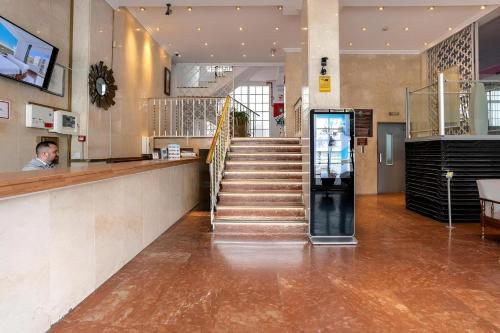 a lobby with a staircase and a man at a counter at BLUESEA Torremolinos Centro in Torremolinos