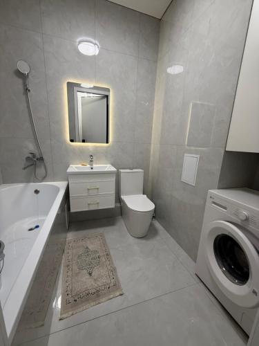 a bathroom with a sink toilet and a washing machine at Жк Берекелы in Almaty