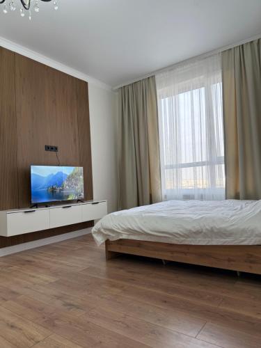 a bedroom with a bed and a flat screen tv at Жк Берекелы in Almaty