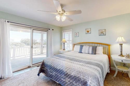 a bedroom with a bed with a ceiling fan and a window at Buhlers Day Off in Corolla