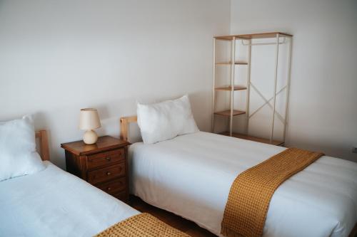 a bedroom with two beds and a night stand with a lamp at Casa Magenta - Alojamento Local in Trofa