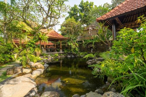a garden with a pond in front of a house at Aksara Ubud in Ubud