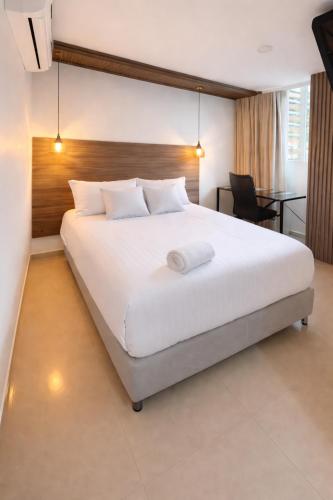 a bedroom with a large white bed and a desk at Hotel Sun Suite in Barranquilla