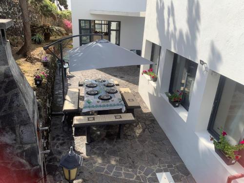 an outdoor patio with a table and an umbrella at Surf & Guest Lorena´s House in Ribeira Grande