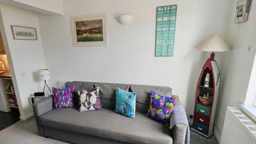 a living room with a gray couch with colorful pillows at One Fisherman's Loft in Brixham