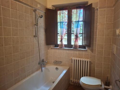 a bathroom with a tub and a toilet and a window at Garbo Home in Asciano