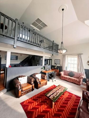 a living room with leather furniture and a staircase at The Old Court House & Jail in Menai Bridge