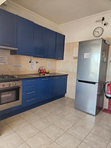 a kitchen with blue cabinets and a stainless steel refrigerator at Zabava Odivelas in Odivelas