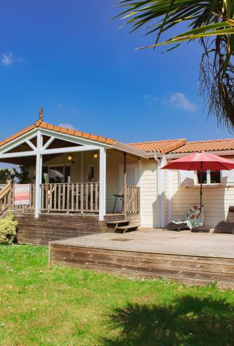 a house with a deck and an umbrella at Le Clos des Soulacaises in Soulac-sur-Mer