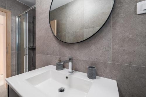 a bathroom with a white sink and a mirror at Apartments Rea in Krk