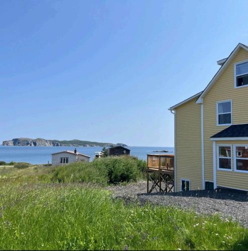 a house with a deck next to a body of water at Wild Cove Retreat & Nook in Twillingate