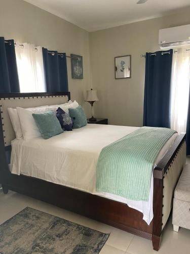 a bedroom with a large bed with blue curtains at The Full Maison at Ocho Rios in Ocho Rios