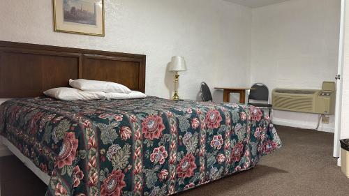a hotel room with a bed with a floral bedspread at Economy Inn Motel in Kingman
