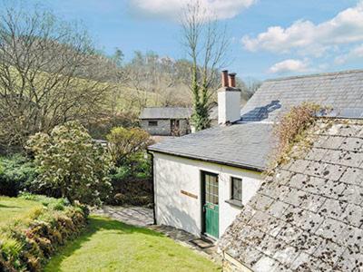 a white house with a green door in a yard at Stream Cottage - 27550 in Wheddon Cross
