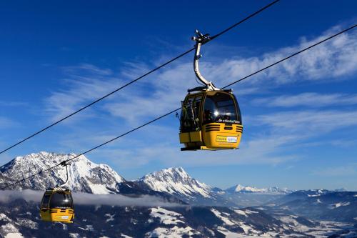 two cable cars flying over a snow covered mountain at Appartement Alpenglück in Aich