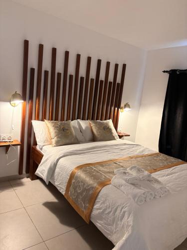 a bedroom with a large bed with a wooden headboard at Relax Appart Hôtel in Kourou