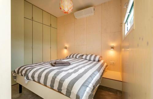 a bedroom with a bed with a black and white striped comforter at De Lepelaar - Ecohuisjes Terschelling in Midsland