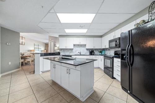 a large kitchen with white cabinets and black appliances at The Palms West Unit 515 in Orange Beach