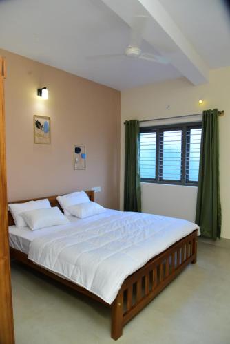 a bedroom with a large bed with white sheets at Nirantara Luxury Service Apartment in Gonikoppal