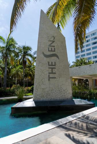 a monument in front of a building with palm trees at The Sens Cancun by Oasis - All Inclusive in Cancún