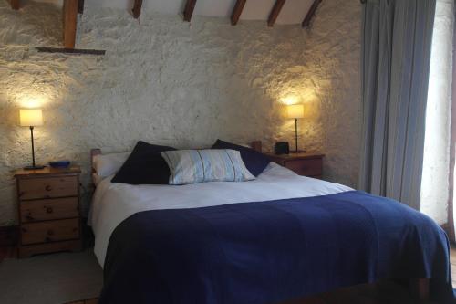 a bedroom with a bed with two night stands and two lamps at The Old Barn in Rhoose