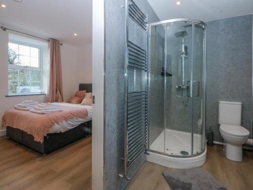 a bathroom with a shower and a bed in a room at Gate House in Llangefni