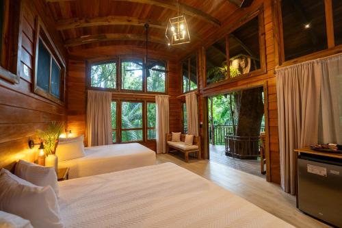 a bedroom with two beds and a large window at Maquenque Lodge in Boca Tapada