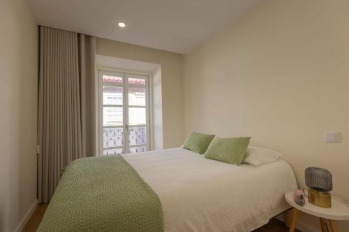 a bedroom with a white bed and a window at Coração dos Arcos in Arcos de Valdevez