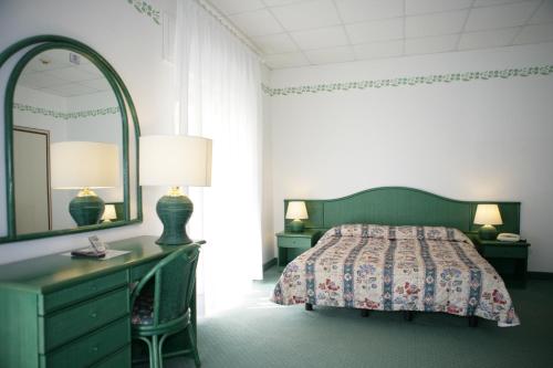 um quarto com uma cama, uma cómoda e um espelho em Hotel Diana em Grado