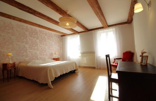 a bedroom with a bed and a table and windows at Chambre n5 Maison dHôtes de Charme in Maizières
