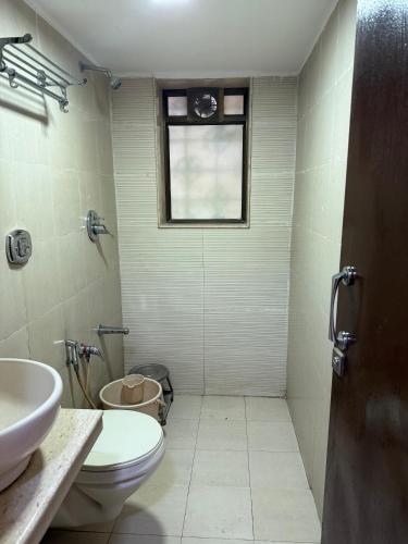 a bathroom with a toilet and a sink and a window at Hotel Sweet Inn in Mumbai