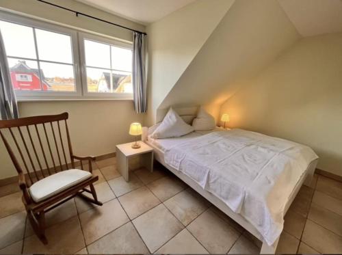 a bedroom with a bed and a chair and a window at Wellenläufer Breege in Breege