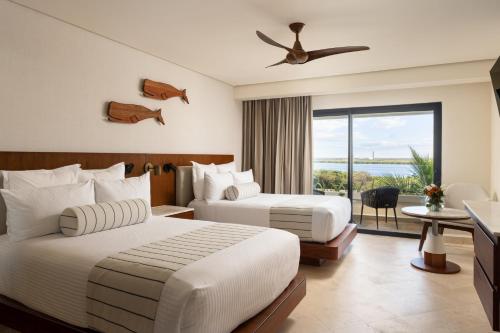 two beds in a hotel room with a view of the ocean at Secrets Mirabel Cancún Resort & Spa - Adults Only - New Spa now open! in Cancún