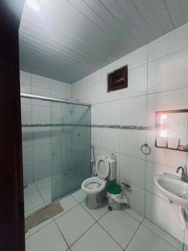 a bathroom with a shower and a toilet and a sink at Pousada e Chalés mar e sol in Manibu