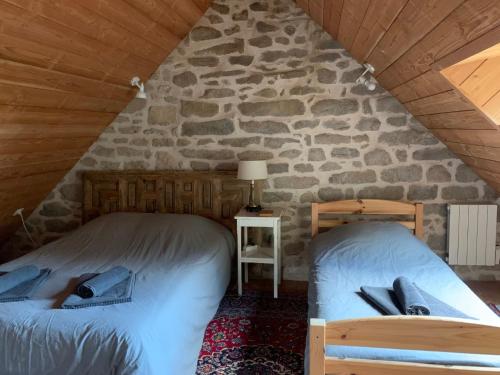 two beds in a room with a stone wall at La maison de Baptiste La Monédière in Chaumeil