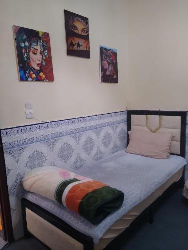 a small bed in a room with pictures on the wall at Casa di Medina - Authentic Stay with Parking in Tiznit