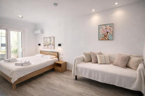 a white bedroom with a bed and a couch at Eleni`s apartment Gialova, Giorgos House in Gialova