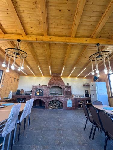 a room with a brick fireplace and tables and chairs at Șoaptele Naturii A-frame in Buzău