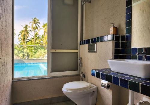 a bathroom with a toilet and a sink and a pool at Beach 7 mins walk Luxury villa Diva in Calangute