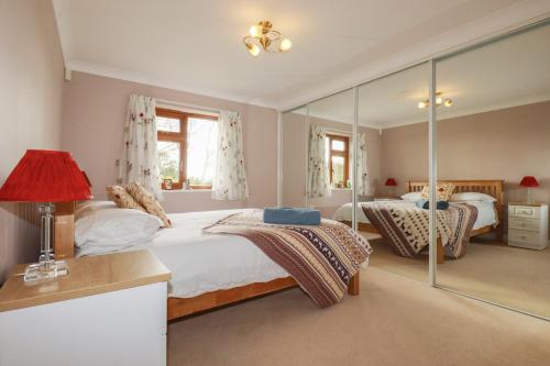 a bedroom with two beds and a red lamp at Honeysuckle Rise in Looe