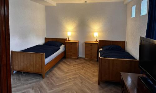 two beds in a room with two night stands and a television at Monteurwohnung Inzlingen nahe Basel in Inzlingen