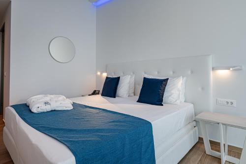 a bedroom with a large bed with blue and white pillows at Mirage Bleu Hotel in Tragaki